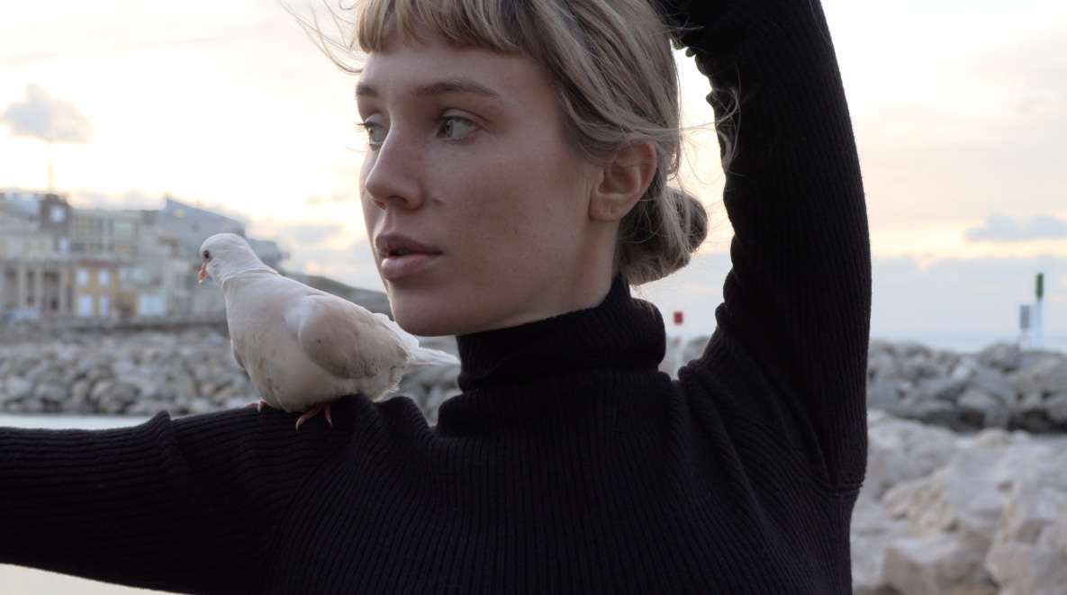 Photographie d'une femme et d'un oiseau sur son épaule.