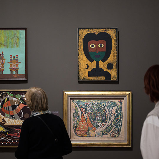 Visiteurs devant des toiles lors d'une exposition.