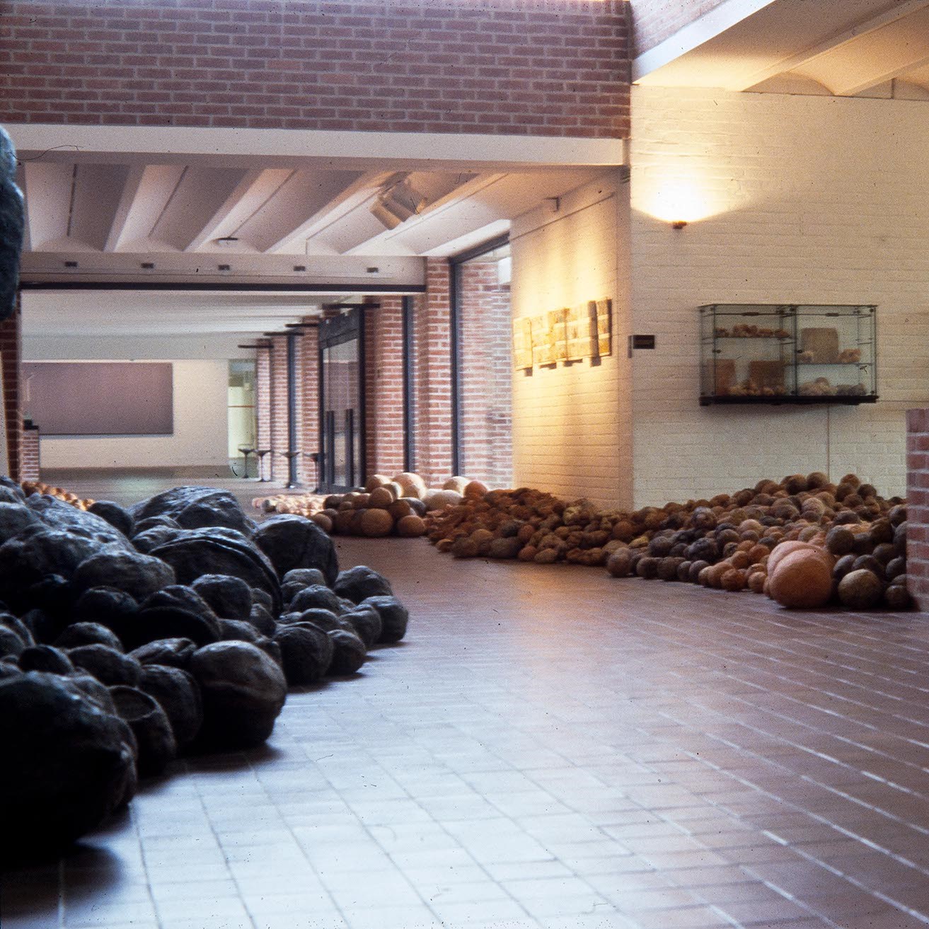 Haul d'entrée du musée envahit par une œuvre, de multiples boules s'acculent contre les parois.