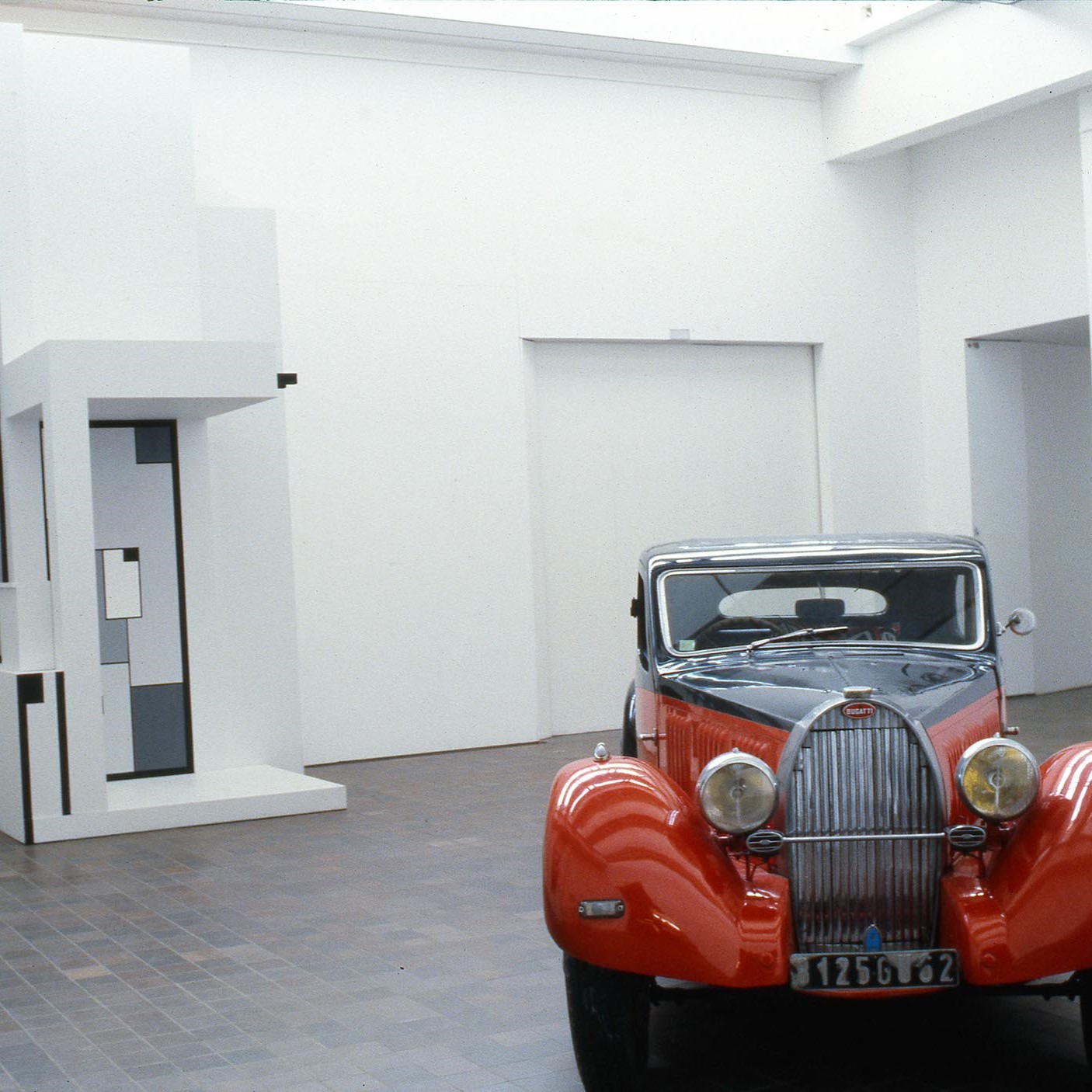 Salle d'exposition du musée avec une voiture rouge.