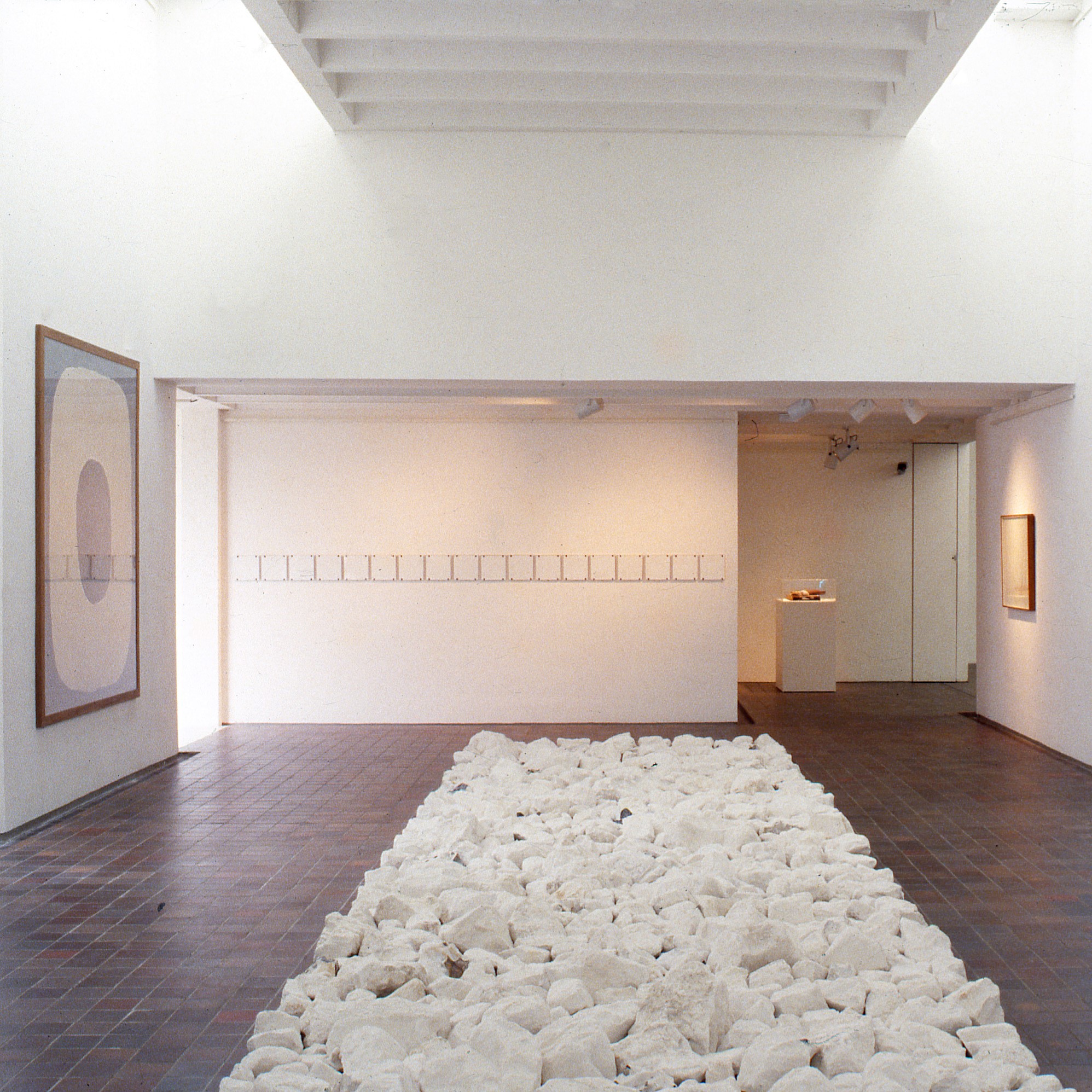 Salle d'exposition du musée avec un centre composé de pierres blanches.