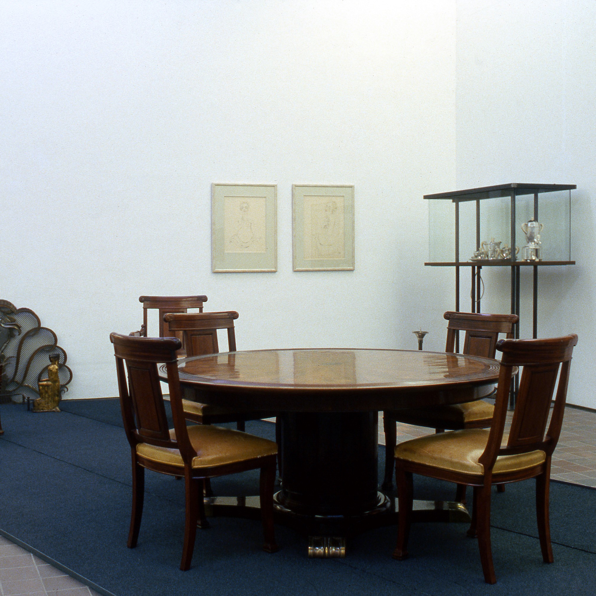 Salle d'exposition présentant du mobilier d'art décoratif, table et chaises.