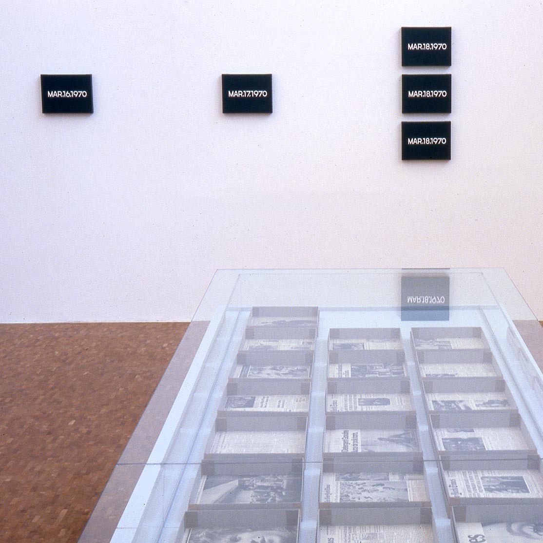 Salle d'exposition avec vitrine et œuvres au mur.