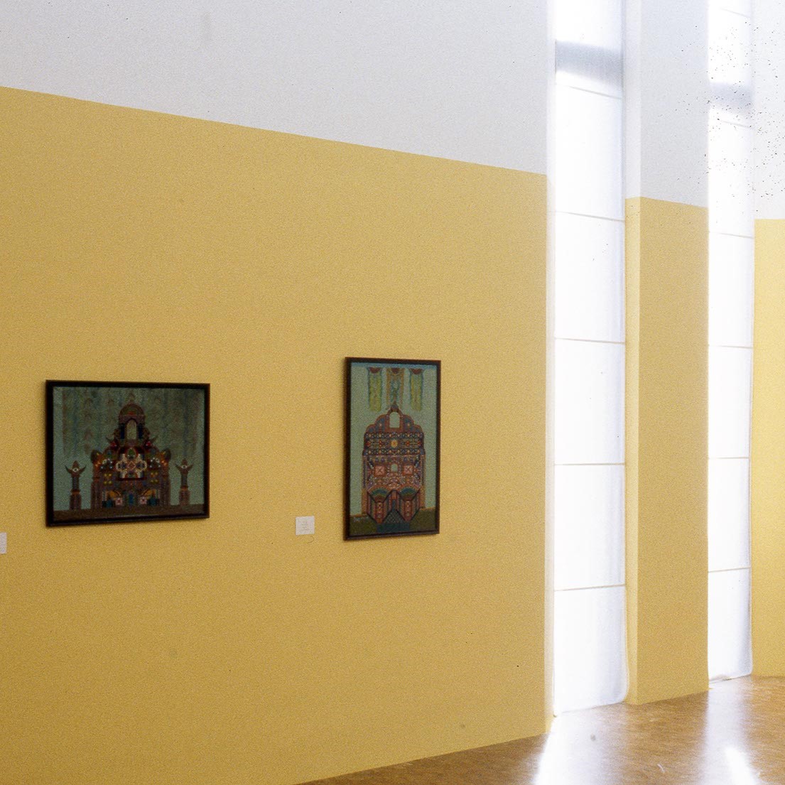 Deux toiles sur un mur jaune.