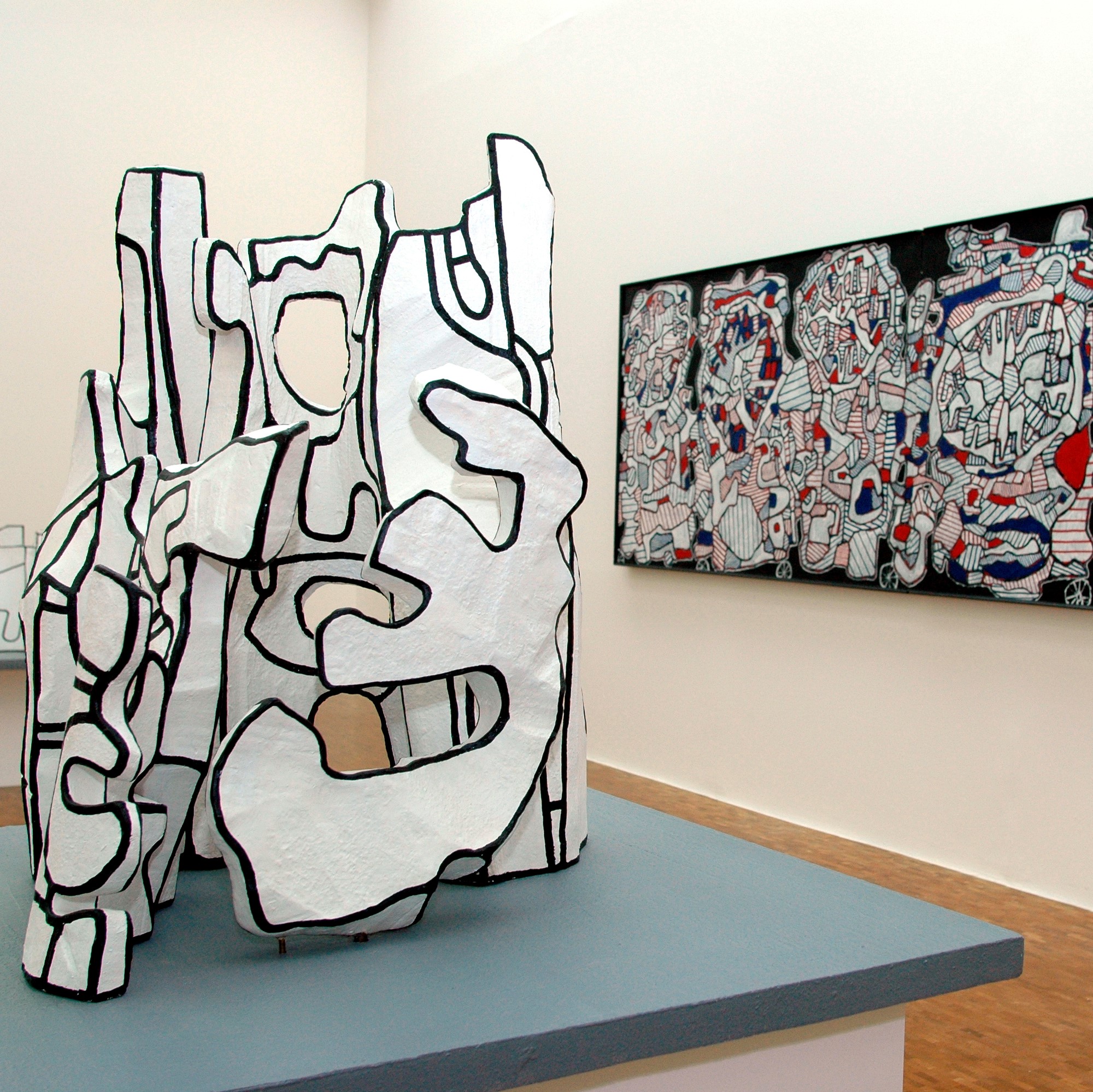 Salle d'exposition, sculptures au centre et toile au mur.