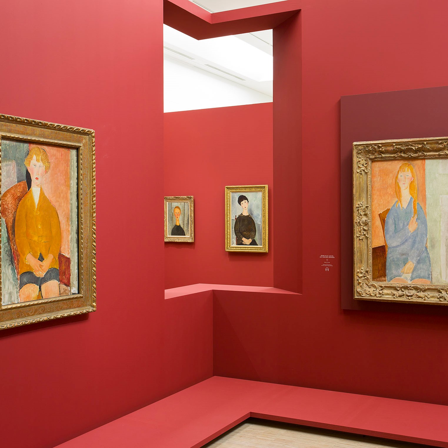 Salle d'exposition rouge avec quatre toiles de Modigliani.