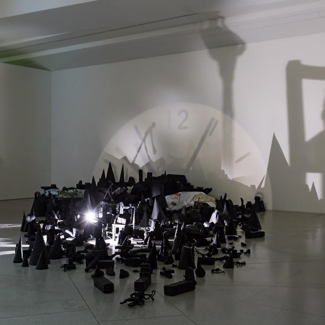 Installation d'objets et d'un projecteur formant des ombres sur le mur.