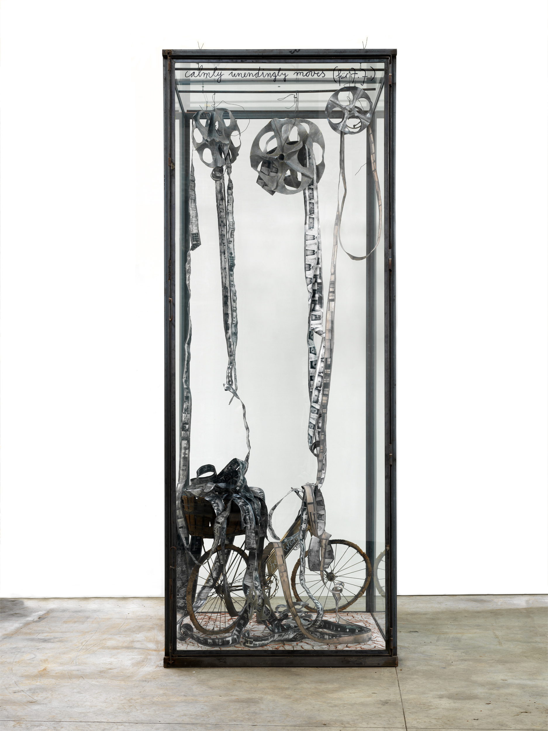 Anselm Kiefer, Calmly Unendingly Moves. Œuvre sculpturale grise, une vélo se retrouve enseveli de pellicules. 