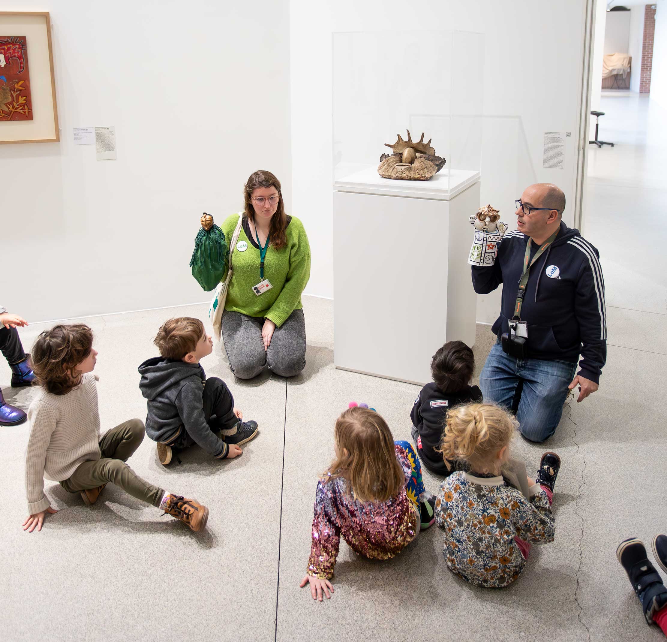 Groupe d'enfants regardant les guides avec des marionnettes et les œuvres du musée dans le cadre d'un atelier.