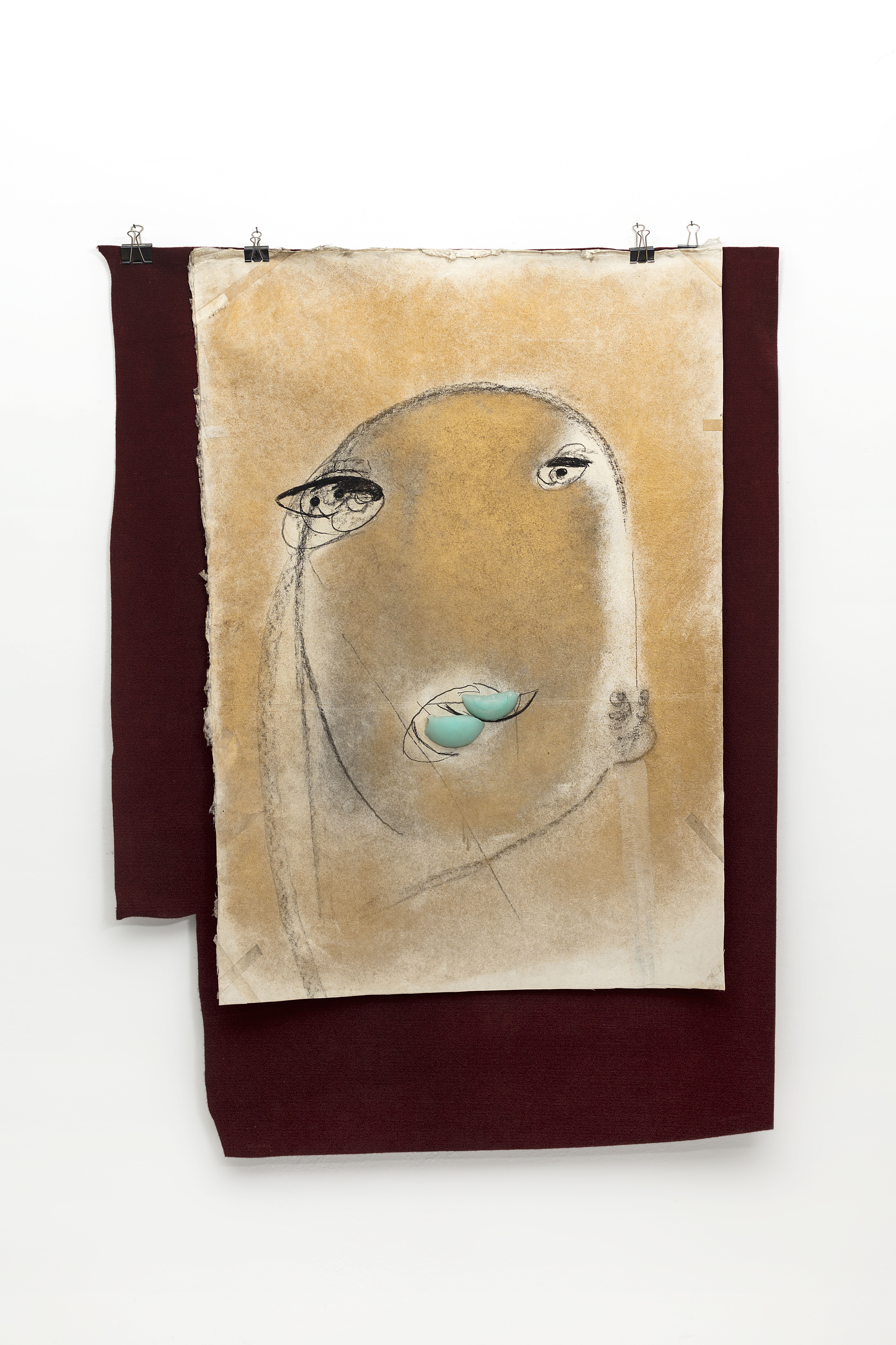 Œuvre pictural de Marisa Merz représentant un visage sur du papier avec un fond en tissus.