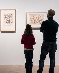 Deux visiteurs devant des toiles.