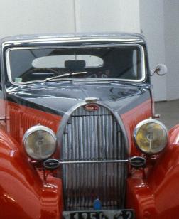 Salle d'exposition du musée avec une voiture rouge.