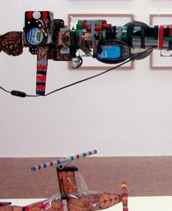 Œuvres représentant des armes en plastique de Robillard suspendues devant des dessins.