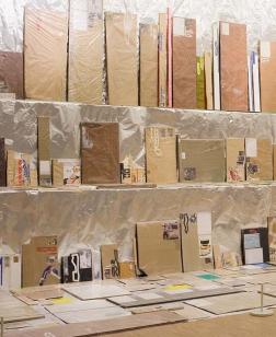 Salle d'exposition avec œuvres sur plusieurs niveaux au mur.