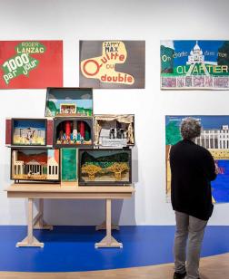 Vue de l'exposition de Guy Brunet. Un visiteur regardant des œuvres accrochées au mur.