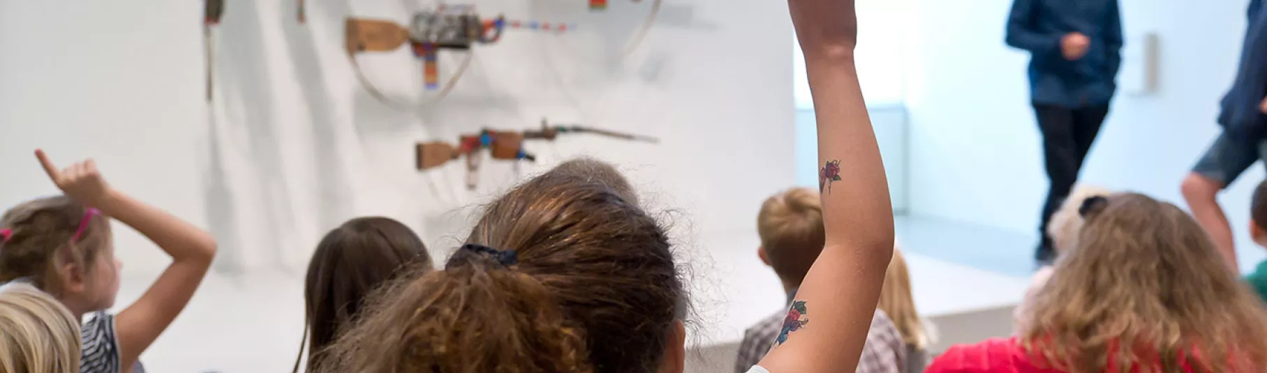 Groupe d'enfants regardant un guide présenter des œuvres de la collection du musée.
