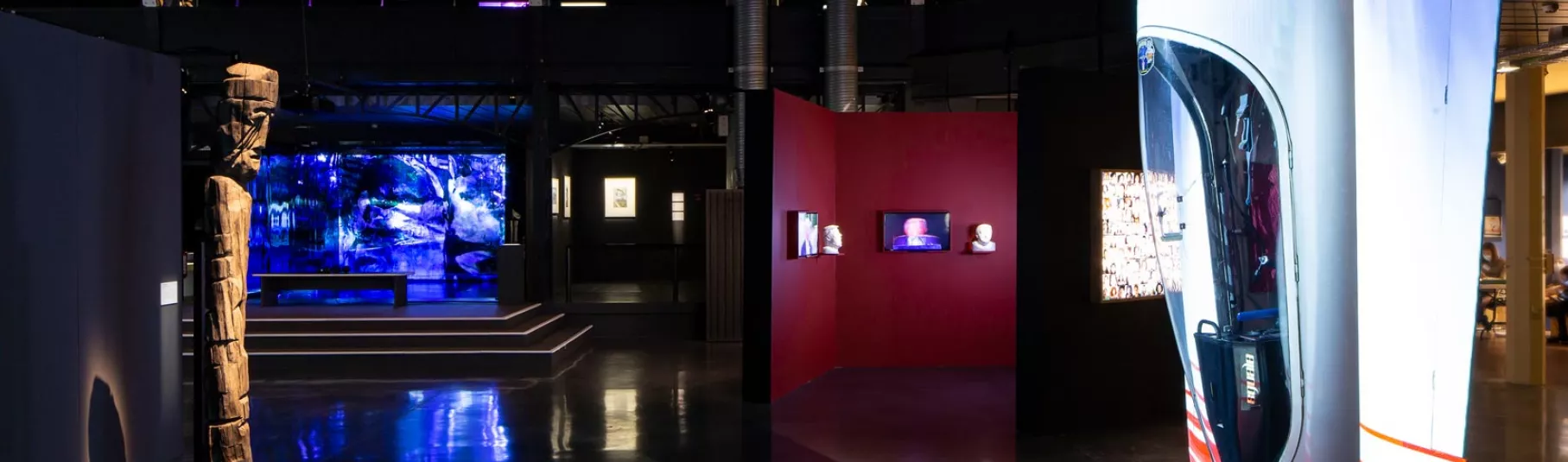 Salle d'exposition dans le noir avec des œuvres sur des sources de lumières.