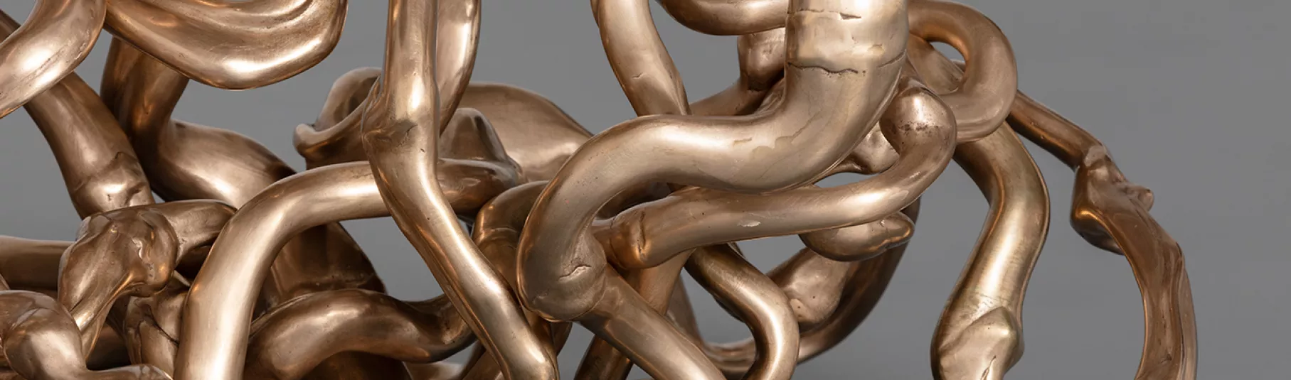 Sculpture dorée représentant des formes organiques s'entremêlant.