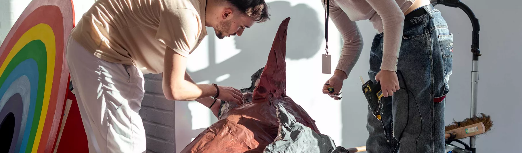 Deux personnes penchées sur des œuvres lors de l'accrochage de l'exposition entre deux mondes.