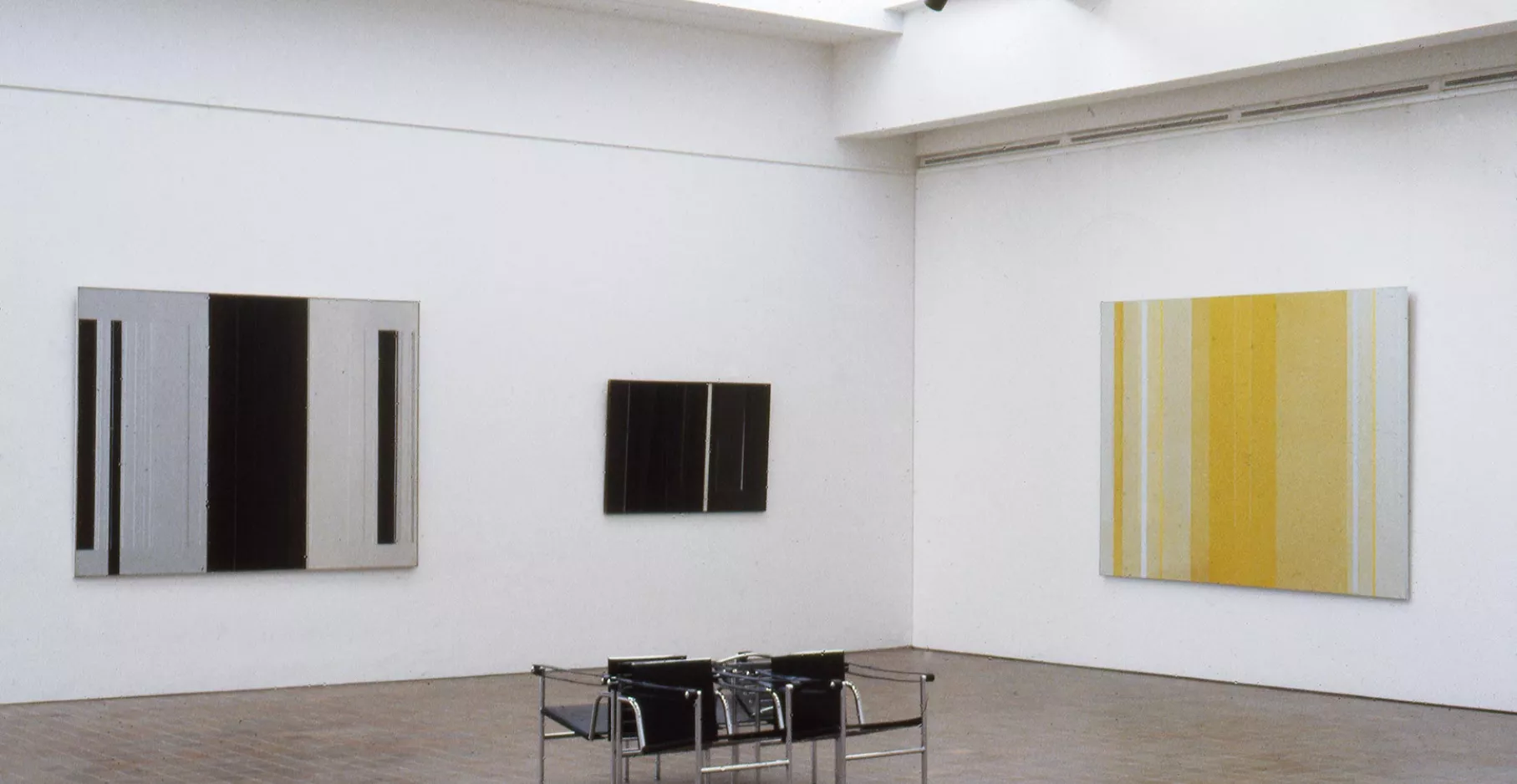 Salle d'exposition du musée présentant trois tableaux aux murs.