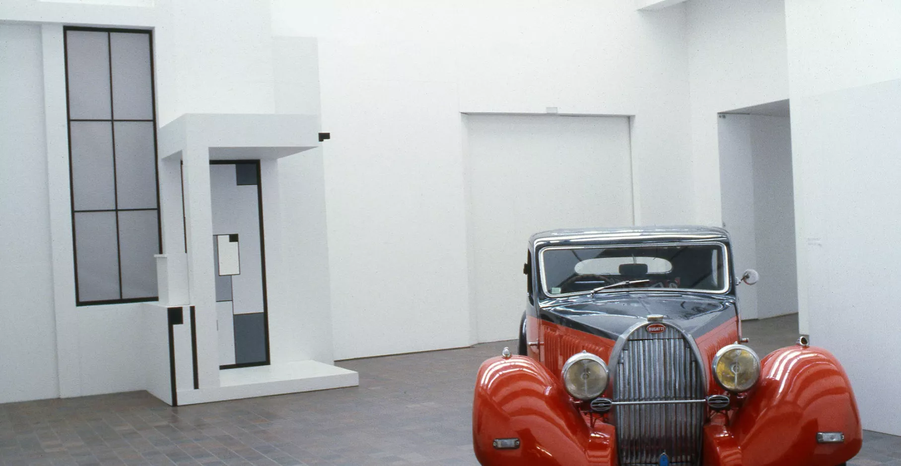 Salle d'exposition du musée avec une voiture rouge.