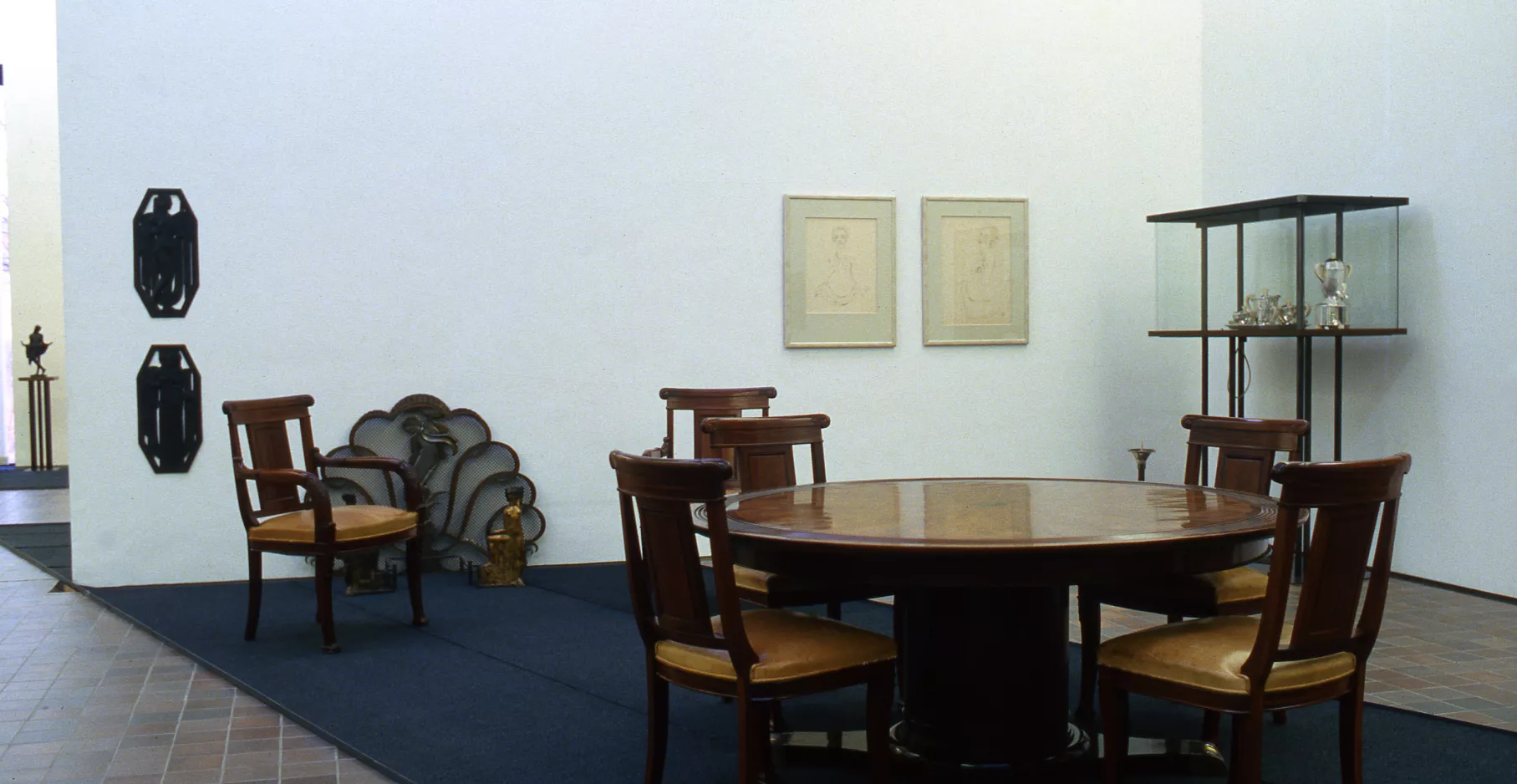 Salle d'exposition présentant du mobilier d'art décoratif, table et chaises.