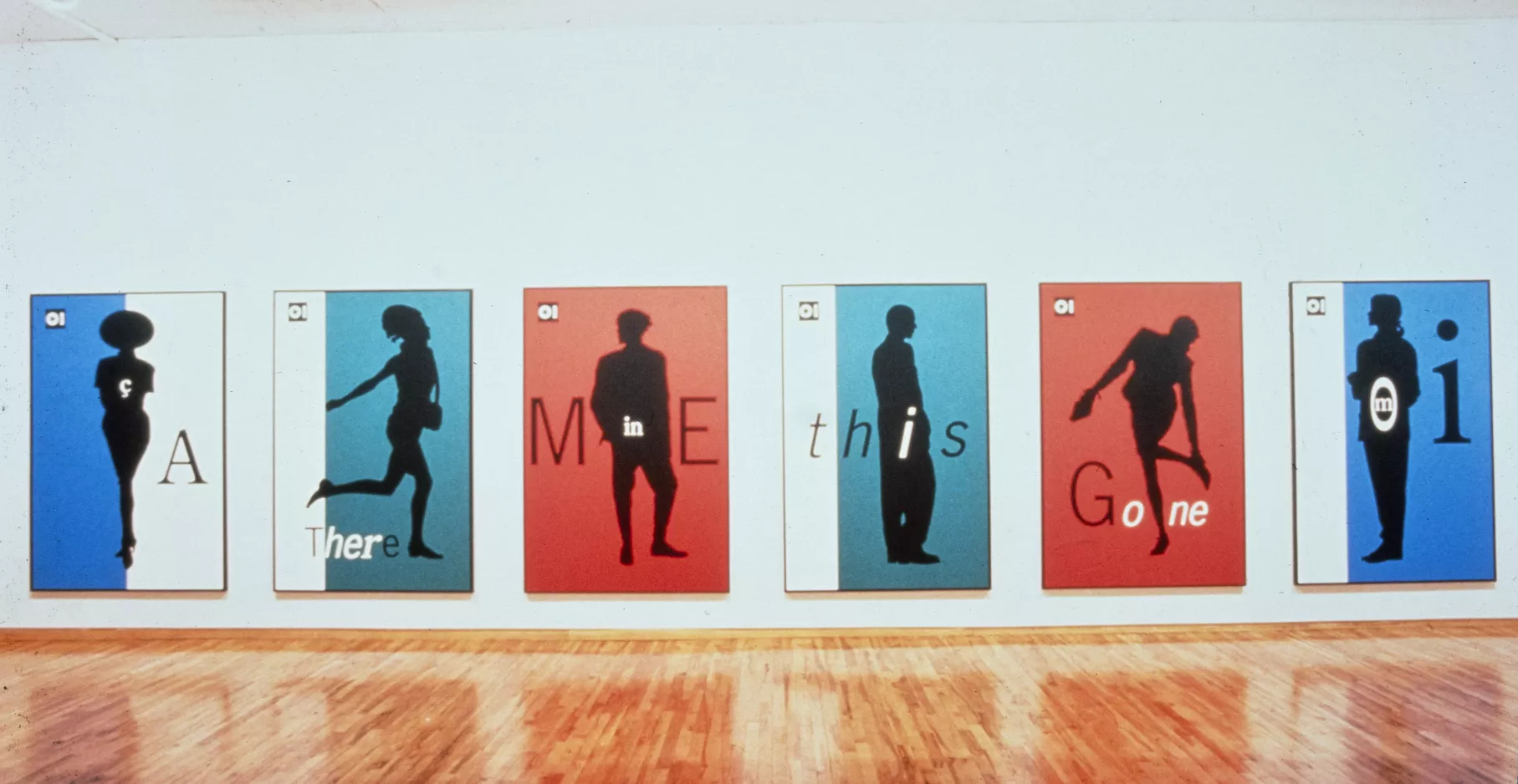 Affiches de couleur bleu ou rouge, accrochées sur un mur blanc du musée.