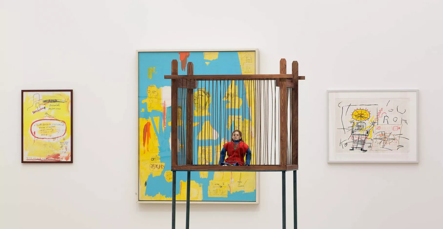 Salle d'exposition avec toiles au mur et installation.