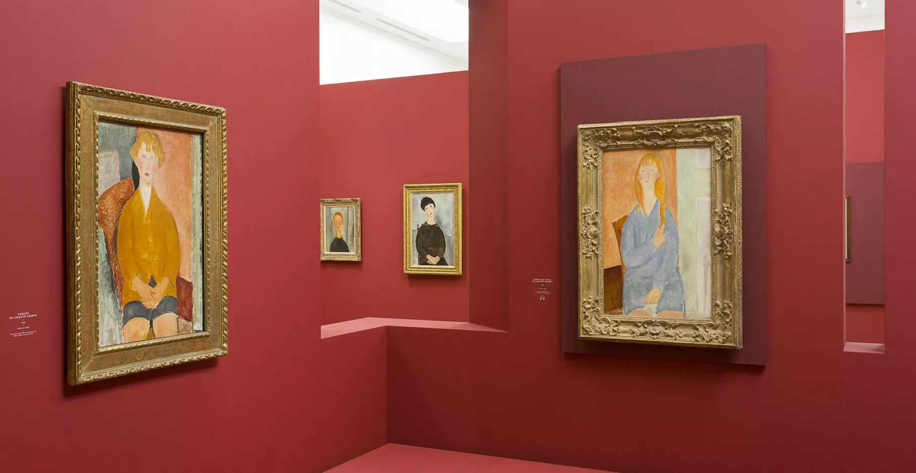 Salle d'exposition rouge avec quatre toiles de Modigliani.