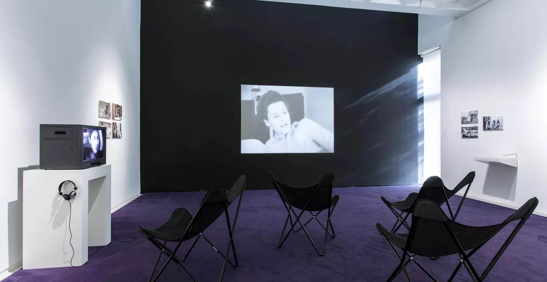 Salle d'exposition du musée où se déroule une projection sur écrans et sur projecteur.