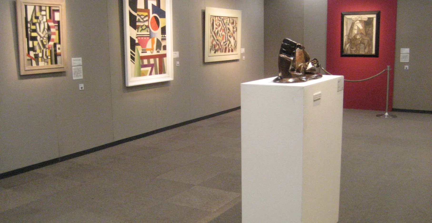 Salle d'exposition ayant une sculpture et quatre tableaux.