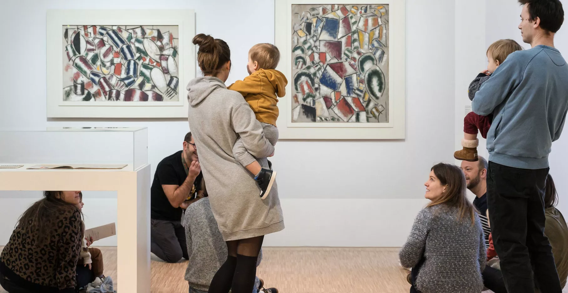 Parents et enfants dans une salle d'exposition en train de regarder des œuvres.