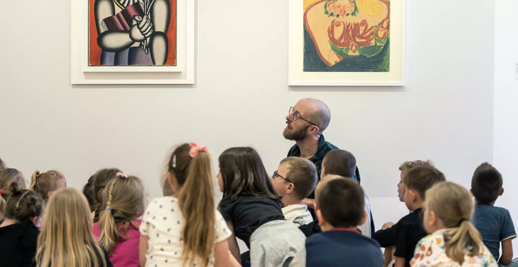 Groupe d'enfants regardant un guide présenter des œuvres de la collection du musée.