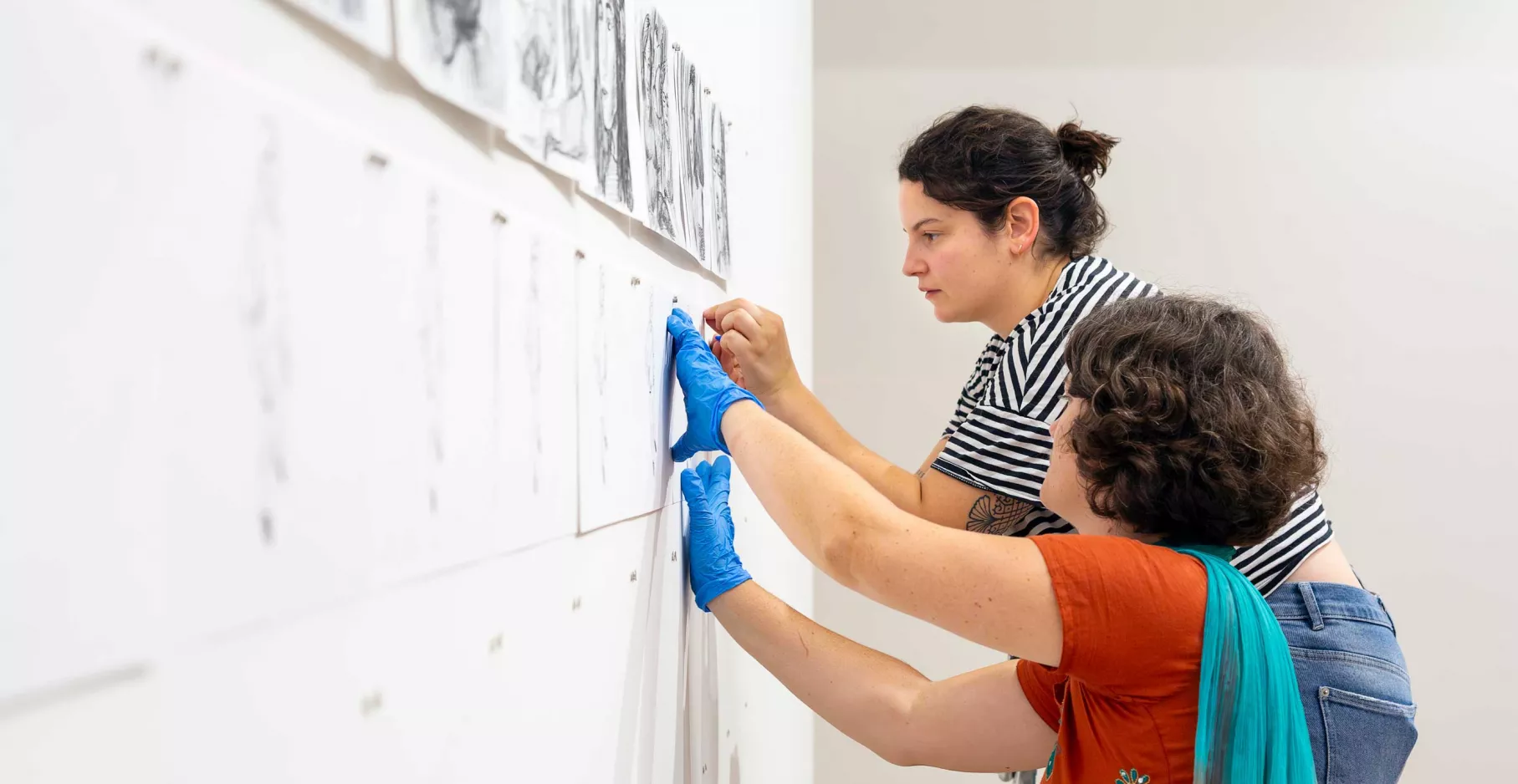 Dessins de Bourouissa en train d'être accrochés sur un mur d'exposition.