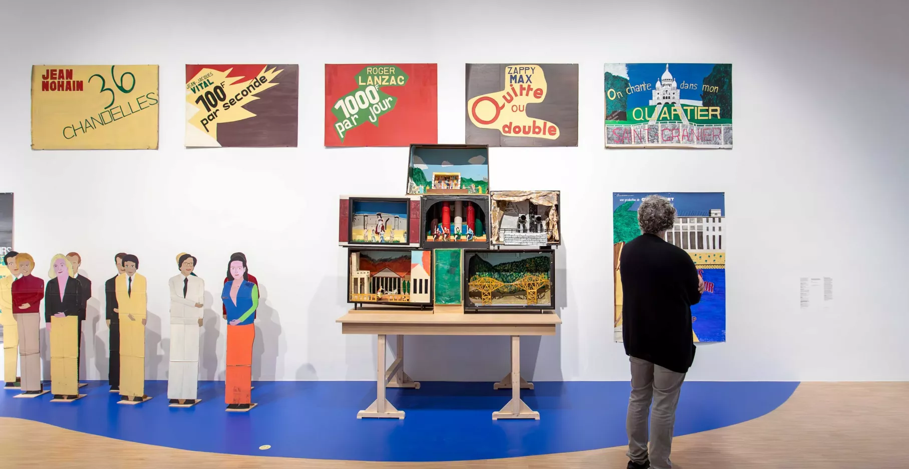 Vue de l'exposition de Guy Brunet. Un visiteur regardant des œuvres accrochées au mur.