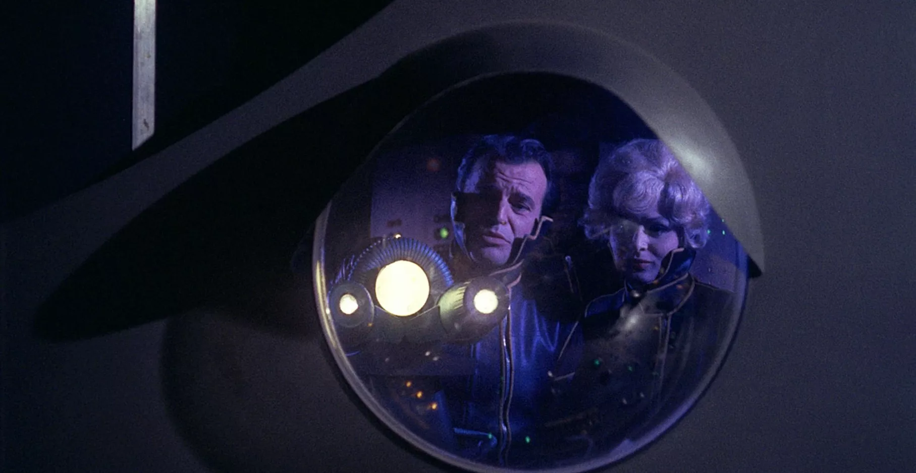 Image du film La planète des vampires. Dans un hublot se trouve un reflet deux personnages.