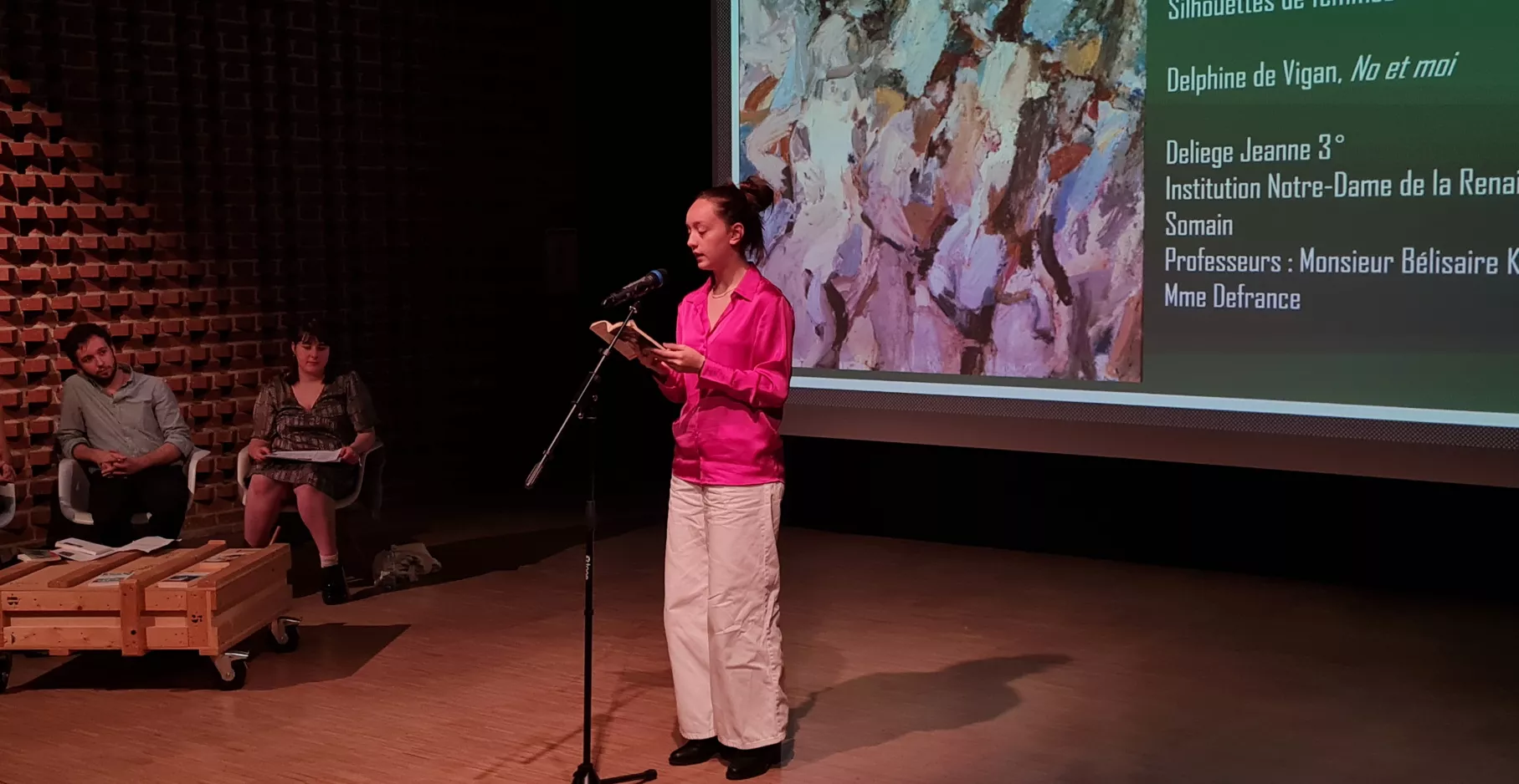 Photo d'une participante au concours "Et si on lisait à voix haute" dans le cadre de lecture à voix haute. En train de lire avec un micro sur la scène.